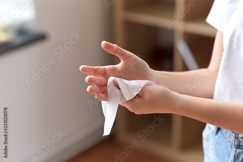 hygiene, health care and disinfection concept - close up of woman cleaning hands with antiseptic wet wipe