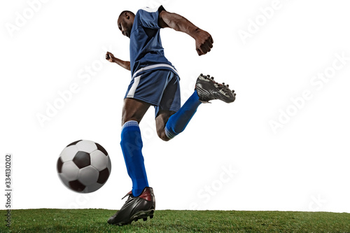 Fototapeta Naklejka Na Ścianę i Meble -  Football or soccer player on white background with grass. Young male sportive model training, practicing. Attacking, catching. Concept of sport, competition, winning, motion, overcoming. Wide angle.