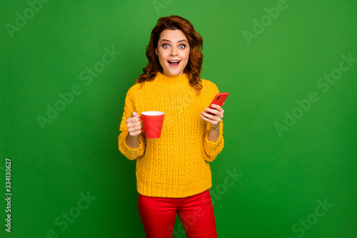 Surprised shocked crazy woman rest relax hold mug hot caffeine beverage use smartphone impressed followers scream wear jumper sweater trousers pants isolated bright shine color background