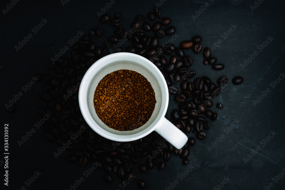 Top view of Instant coffee in cup on dark background with beans Top view of Instant coffee in cup on dark background with beans