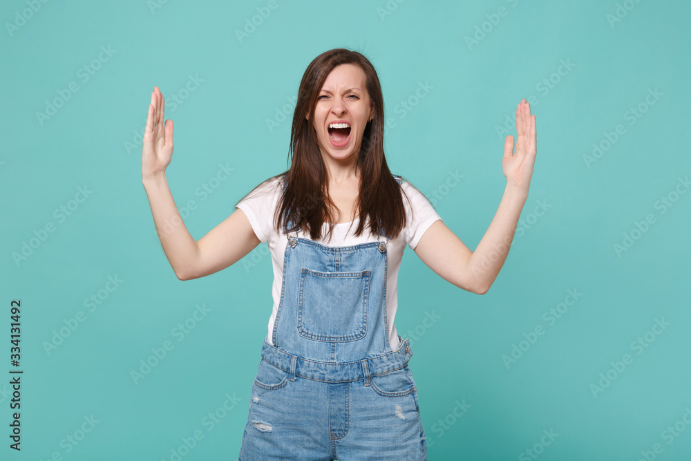 Screaming young brunette woman girl in casual denim clothes isolated on blue turquoise background. People lifestyle concept. Mock up copy space. Gesturing demonstrating size with horizontal workspace. Screaming young brunette woman girl in casual denim clothes isolated on blue turquoise background. People lifestyle concept. Mock up copy space. Gesturing demonstrating size with horizontal workspace.
