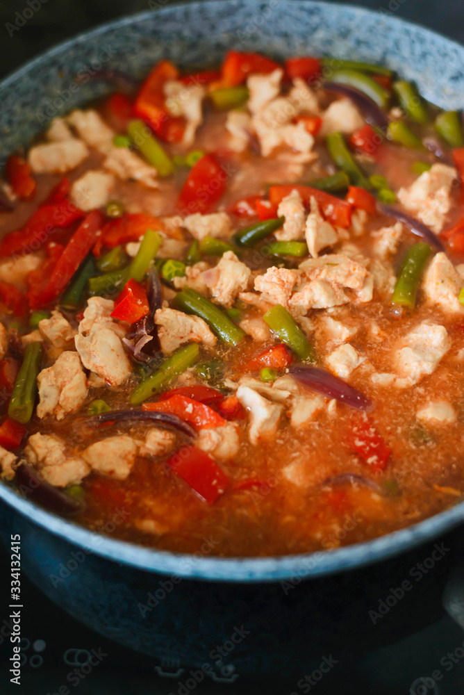 Thai Panang chicken Curry in a frying pan on the stove. Cooking. Boiling. Phanaeng Curry is a Thai dish with chicken, red curry sauce and vegetables. Thai cuisine. Thai food.