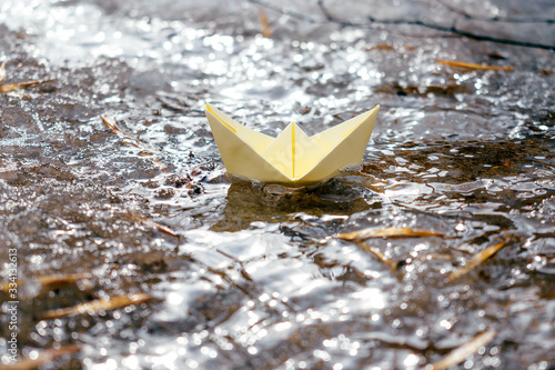  Yellow paper boat sails along the stream. Spring concept.Concept of travel during coronavirus quarantine.Selective focus.