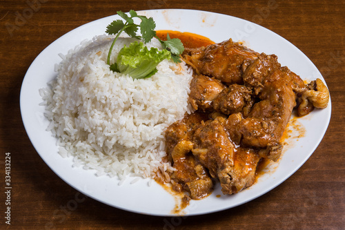 Portion of seco de chivo stewed goat meat with yellow rice and avocado close-up on a plate on the table