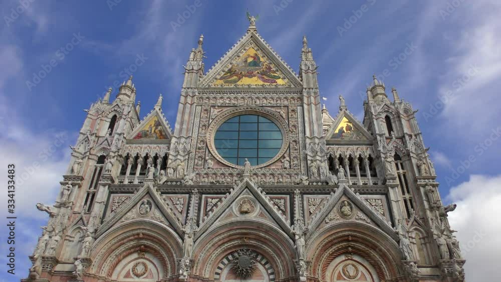 The facade of the Duomo Cathedral in Siena against the background of clouds rapidly moving across the sky. The facade of the Duomo Cathedral in Siena against the background of clouds rapidly moving across the sky.