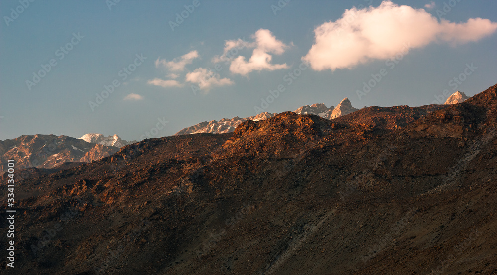 The Himalayan mountains on a clear evening with puffs of clouds in the sky as seen from the village of Nako in Kinnaur in Himachal Pradesh, India.