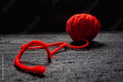 ball of red thread for knitting on black concrete dark background .copy space