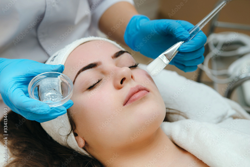 Naklejka premium Beauty salon, cosmetician aplying facial peeling mask. Skin treatment concept.
