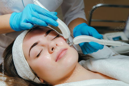 Woman having a stimulating facial treatment from a therapist. Micro-current therapy.