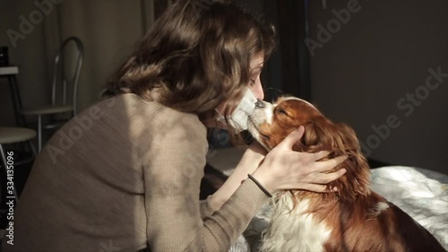 Beautiful European girl kisses her dog through a medical mask.Coronavirus.COVID-19 photo