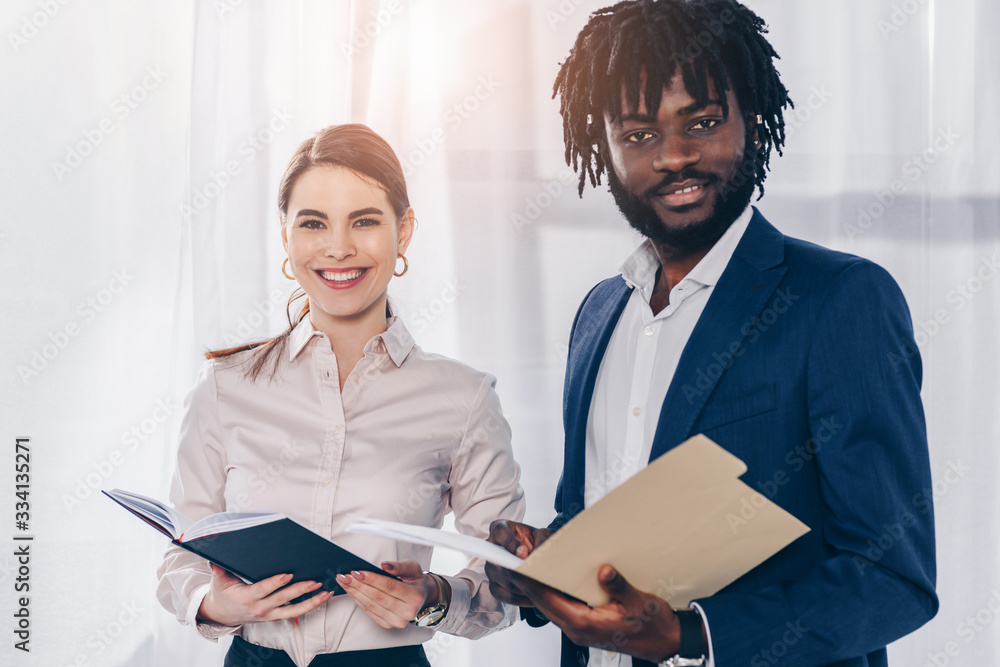African american employer with folder and recruiter with notebook smiling and looking at camera African american employer with folder and recruiter with notebook smiling and looking at camera
