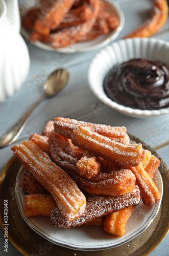 Churros with powdered sugar on a white plate on a wooden background
