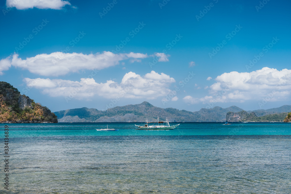 Filippino boats in open ocean in El Nido bay. Islands shapes in background. Palawan island, Philippines