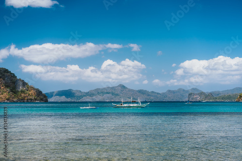 Filippino boats in open ocean in El Nido bay. Islands shapes in background. Palawan island, Philippines