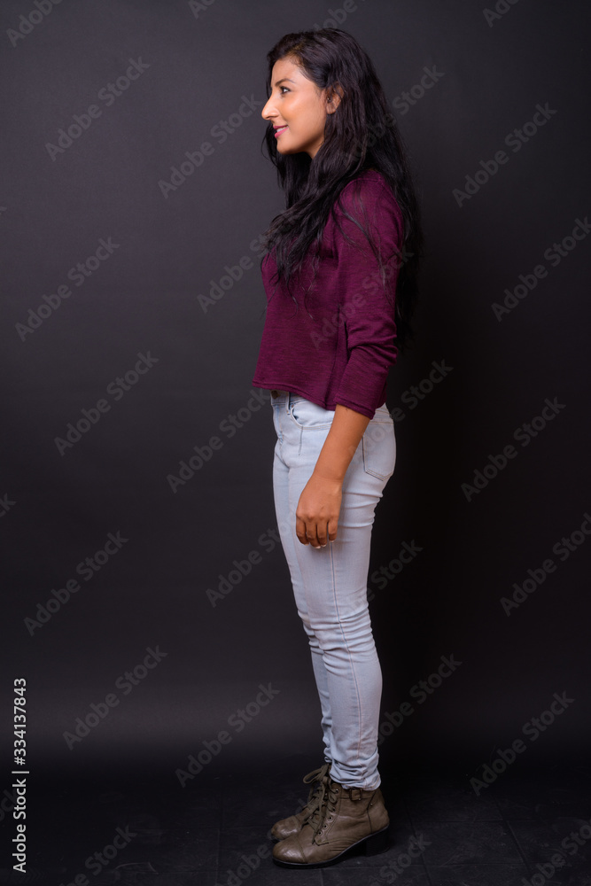Full body shot profile view of happy young beautiful Indian woman smiling Full body shot profile view of happy young beautiful Indian woman smiling