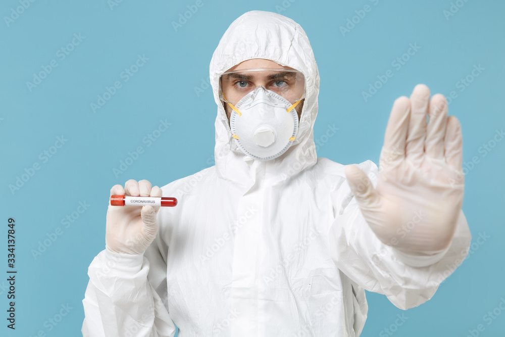 Man in white protective suit respirator mask hold blood test result Sample tube isolated on blue background studio. Epidemic pandemic rapidly spreading coronavirus 2019-ncov medicine flu virus concept Man in white protective suit respirator mask hold blood test result Sample tube isolated on blue background studio. Epidemic pandemic rapidly spreading coronavirus 2019-ncov medicine flu virus concept