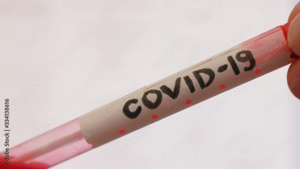 Close up of test tube with red liquid and inscription Covid-19. Acute Respiratory Virus Infection. Illness cold flu. Pandemic. Global spread of coronavirus. Close up of test tube with red liquid and inscription Covid-19. Acute Respiratory Virus Infection. Illness cold flu. Pandemic. Global spread of coronavirus.