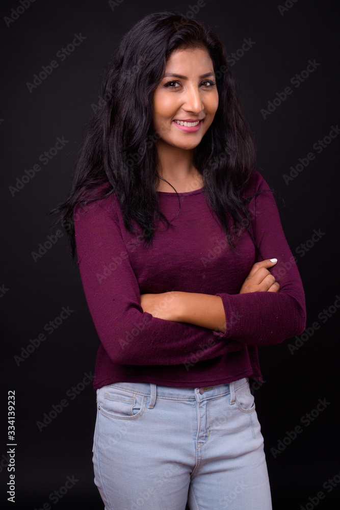 Portrait of happy young beautiful Indian woman thinking with arms crossed Portrait of happy young beautiful Indian woman thinking with arms crossed