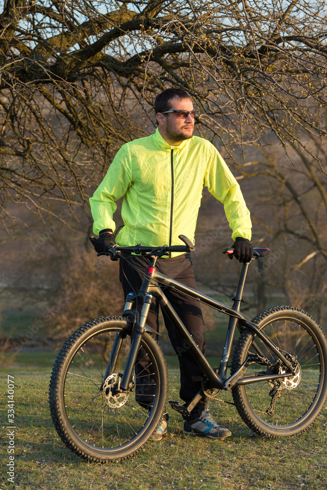 Cyclist in pants and green jacket on a modern carbon hardtail bike with an air suspension fork. The guy on the top of the hill rides a bike. Cyclist in pants and green jacket on a modern carbon hardtail bike with an air suspension fork. The guy on the top of the hill rides a bike.