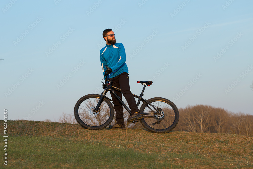 Cyclist in pants and fleece jacket on a modern carbon hardtail bike with an air suspension fork. The guy on the top of the hill rides a bike. Cyclist in pants and fleece jacket on a modern carbon hardtail bike with an air suspension fork. The guy on the top of the hill rides a bike.