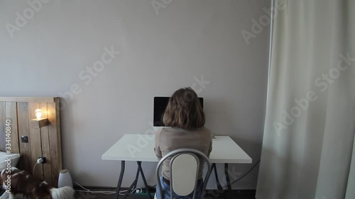 Young attractive girl dresses a protective mask sitting at a table with a computer in isolation.Coronavirus.COVID-19 photo