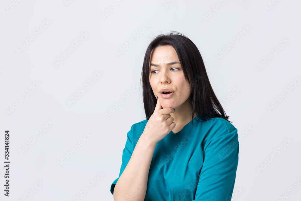 Portrait of a beautiful girl in a blue t-shirt, looks aside with pensive expression, is considering a plan for further action. Portrait of a beautiful girl in a blue t-shirt, looks aside with pensive expression, is considering a plan for further action.