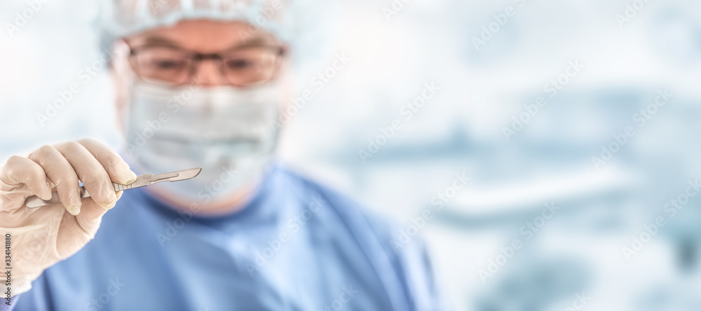 Doctor surgeon specialist with scalpel. In the background blurred the interior of the operating room Doctor surgeon specialist with scalpel. In the background blurred the interior of the operating room