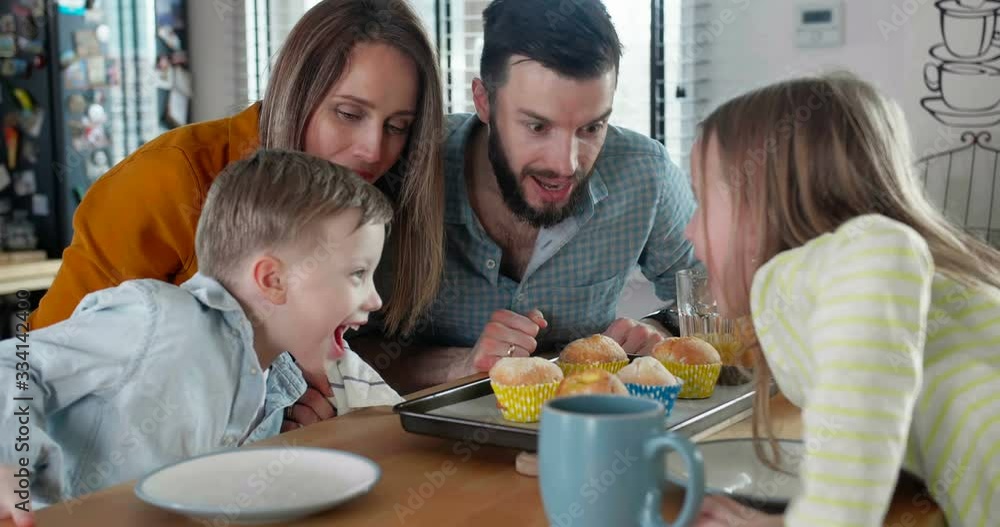 Happy family together concept, young Caucasian mother and father smell hot fresh muffins with kids at home slow motion. Happy family together concept, young Caucasian mother and father smell hot fresh muffins with kids at home slow motion.
