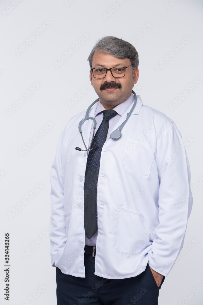 Senior Indian male doctor in white dress, standing with stethoscope over white background Senior Indian male doctor in white dress, standing with stethoscope over white background
