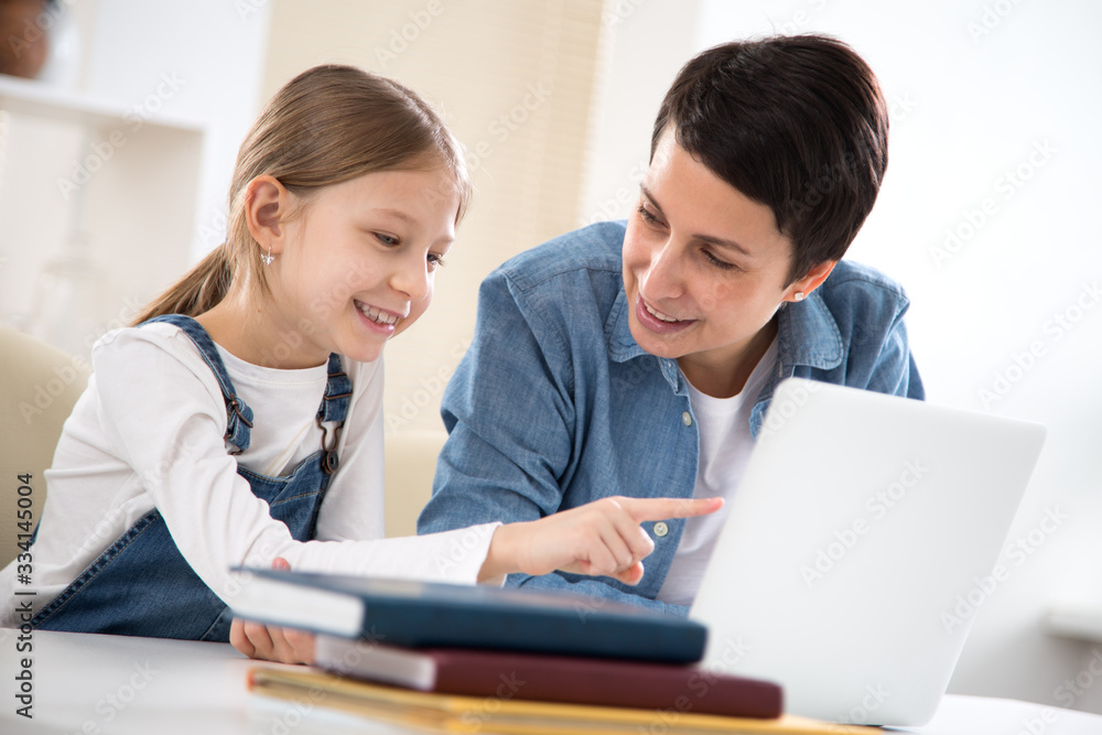 Woman and her little daughter are using a laptop and smiling Woman and her little daughter are using a laptop and smiling