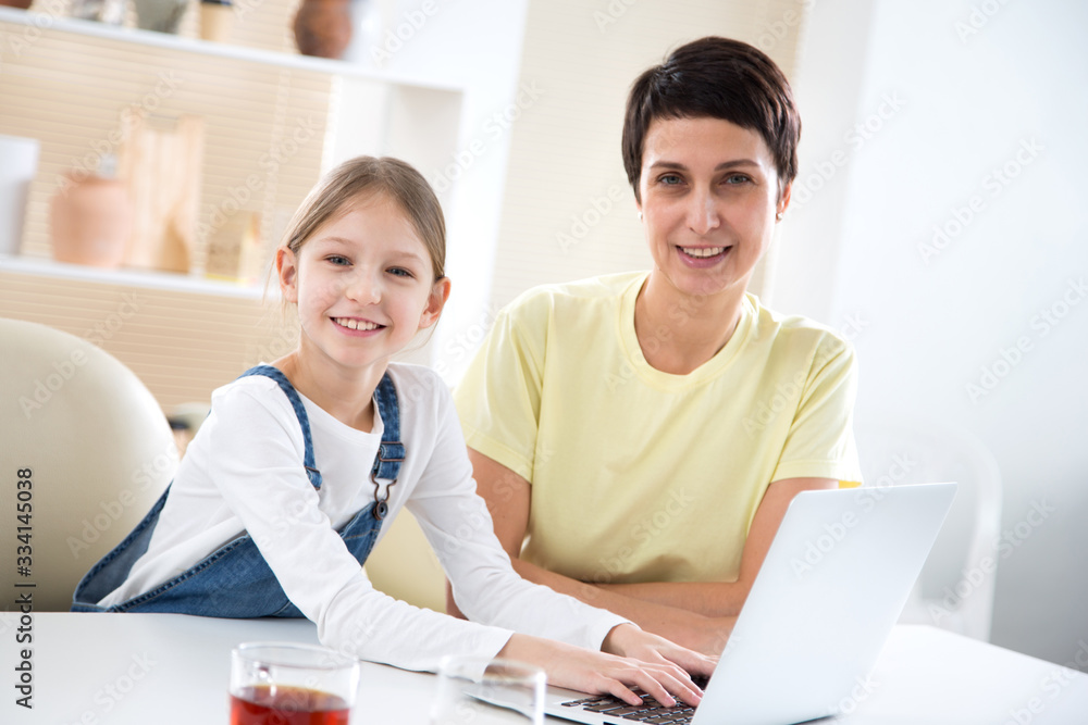 Woman and her little daughter are using a laptop and smiling Woman and her little daughter are using a laptop and smiling