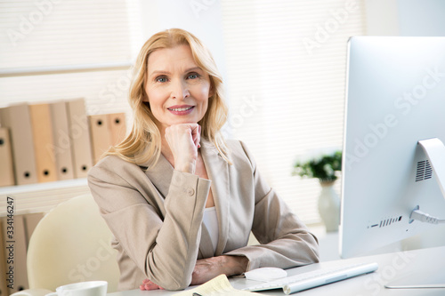 Portrait of senior business woman looking at camera at workplace in an office