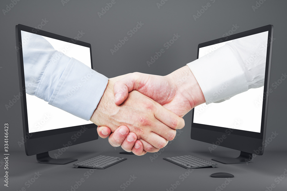 Businessmen shaking hands through computer screens Businessmen shaking hands through computer screens