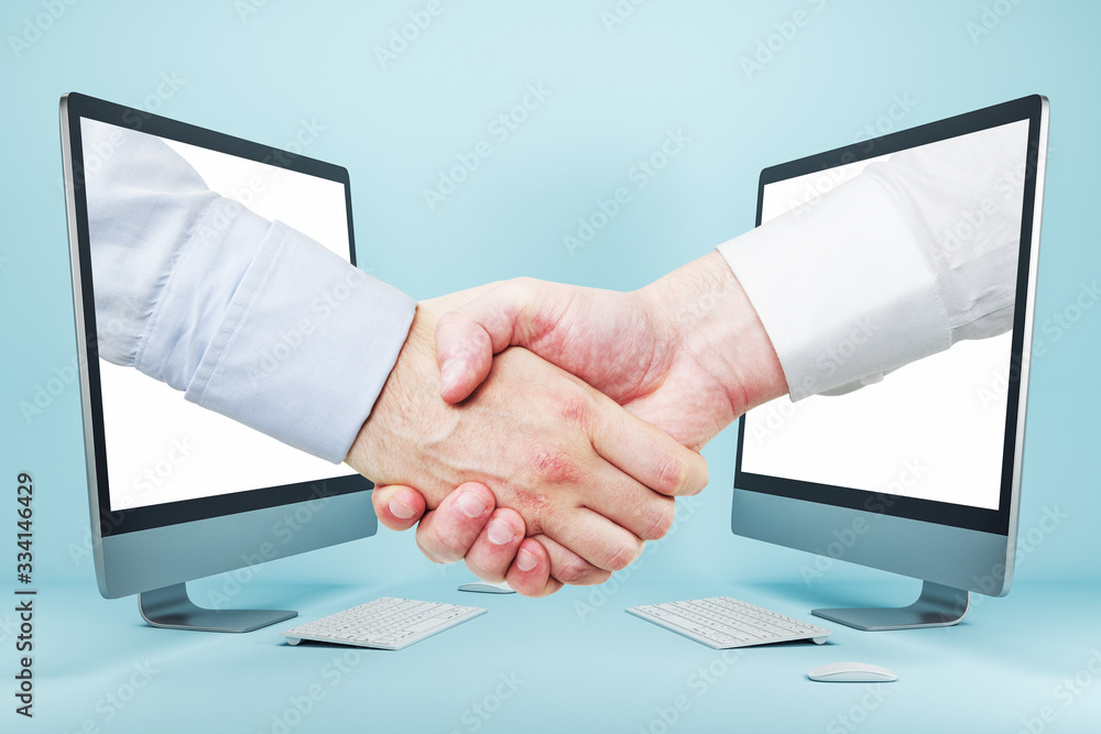 Businessmen shaking hands through computer screens on blue background Businessmen shaking hands through computer screens on blue background