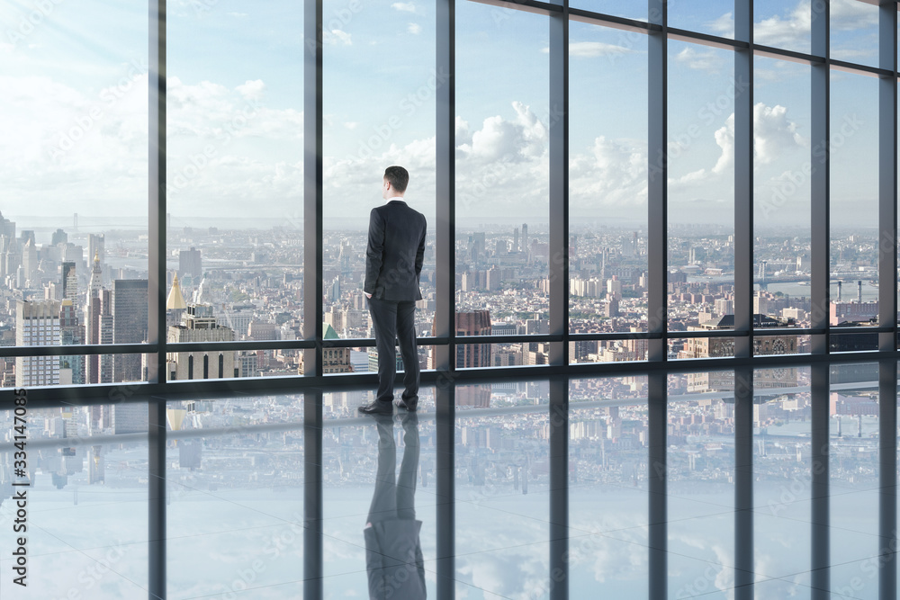 Businessman looking out of window in office interior Businessman looking out of window in office interior