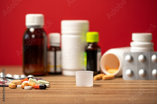 Closeup view photography of many different colorful pills laying on brown wooden surface of table.