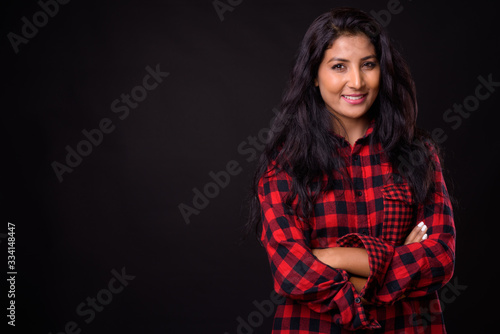 Portrait of happy young beautiful Indian hipster woman smiling with arms crossed
