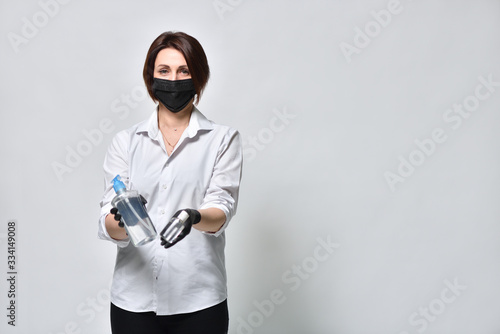 A woman in black gloves demonstrates a protective antiseptic gel on a white background, during the coronavirus pandemic.