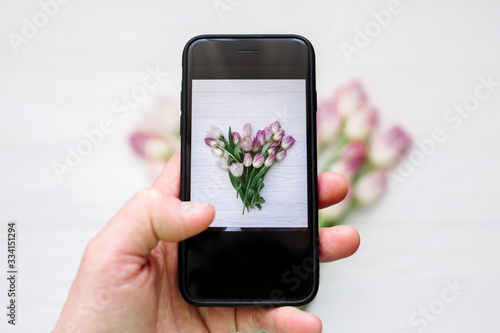Take photo on tulips phone flat ley. Hand with phone
