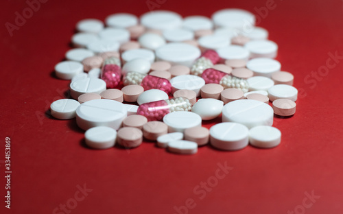 Heap of white pills, tablets, capsules on red background. Drug prescription for treatment medication health care concept wth copy space.