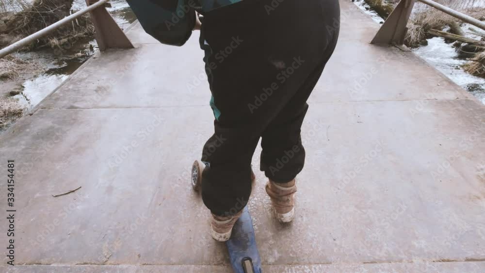 Young girl ride scooter on iron bridge. Nature background. Lifestyle and climate change concept. Eco transport. Stock video. Young girl ride scooter on iron bridge. Nature background. Lifestyle and climate change concept. Eco transport. Stock video.