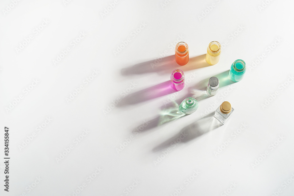 Perfume in a transparent bottle, aromatic oils. Colored shadow on a white background. . Aromatherapy, perfume production. Space for text. Perfume in a transparent bottle, aromatic oils. Colored shadow on a white background. . Aromatherapy, perfume production. Space for text.