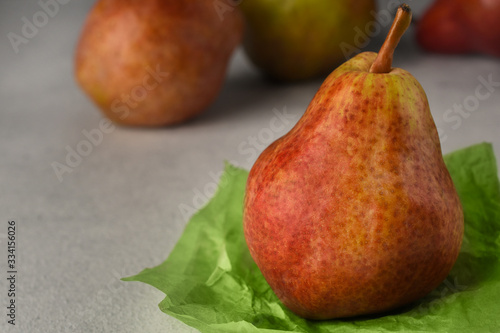 Red ripe pears on a light background. A Pear on a piece of crumpled green wrapping paper and three pears on background. Fruit background. Copy space. Selective focus.