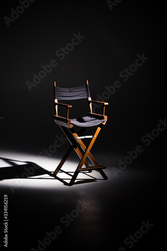 Directors chair stands in the beam of light. Space for text. Vacant chair. The concept of selection and casting. Shadow and light. photo