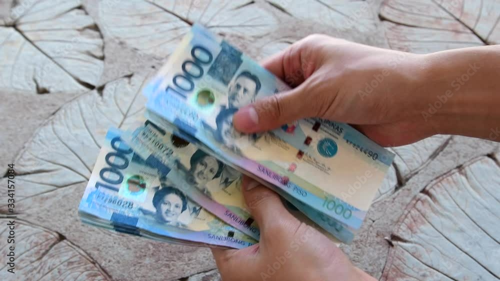 Counting a bulk of 1000 Philippine peso cash on a table by hand