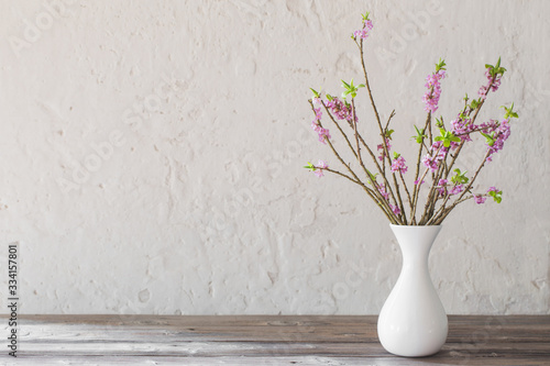 Fototapeta daphne flowers in vase on old wooden table on background white w