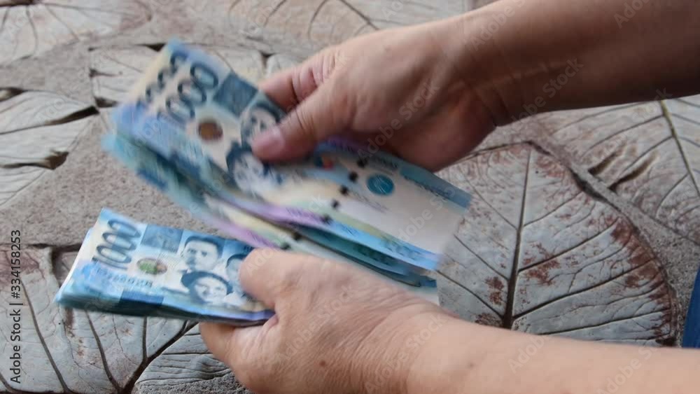 Counting a bulk of 1000 Philippine peso cash on a table by hand