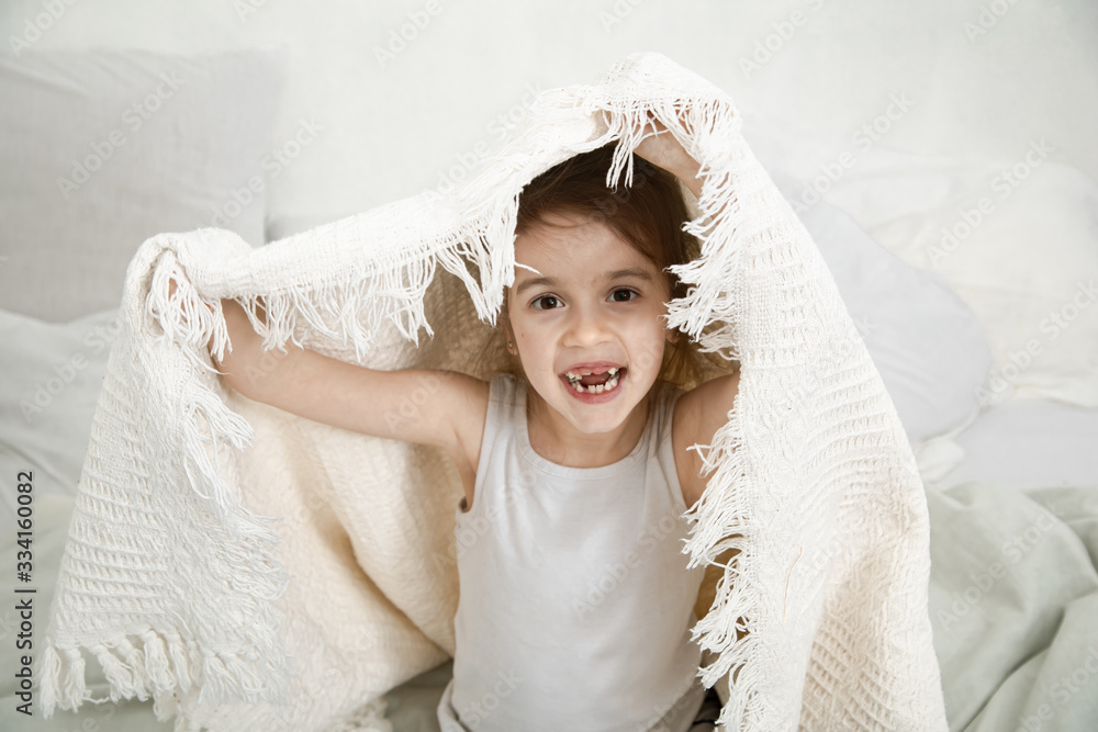 Cute little girl playing in bed with a blanket. Cute little girl playing in bed with a blanket.