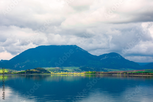 lake in mountains. cloudy day in springtime. beautiful scenery of high fatra mountains in dappled light. wonderful scenery of liptovska mara, slovakia © Pellinni