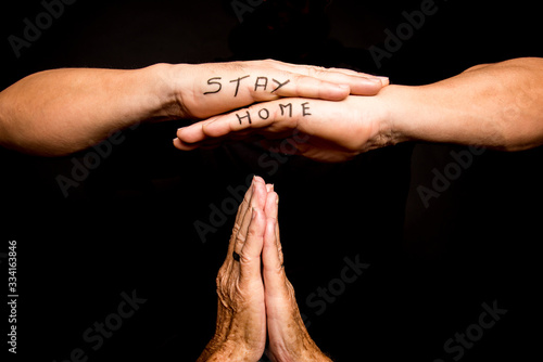 hands overlapped with stay home inscribed in pencil and two hands joined below